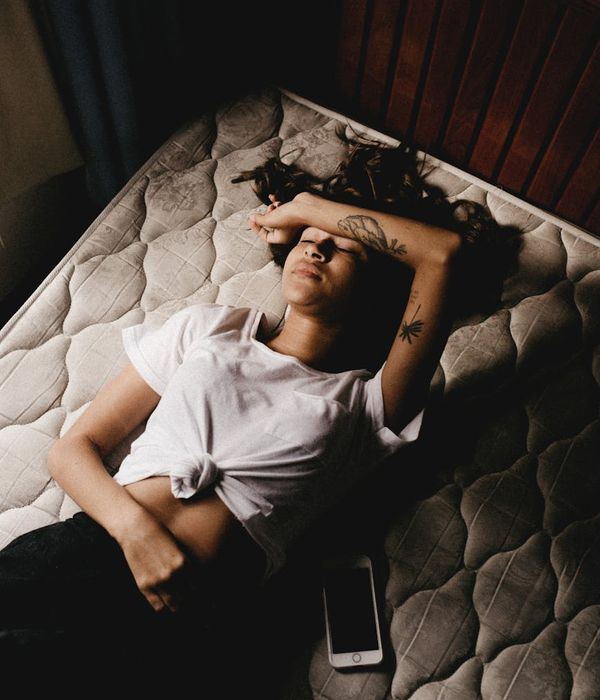 A person in a relaxed pose in a minimalist, dimly lit room.